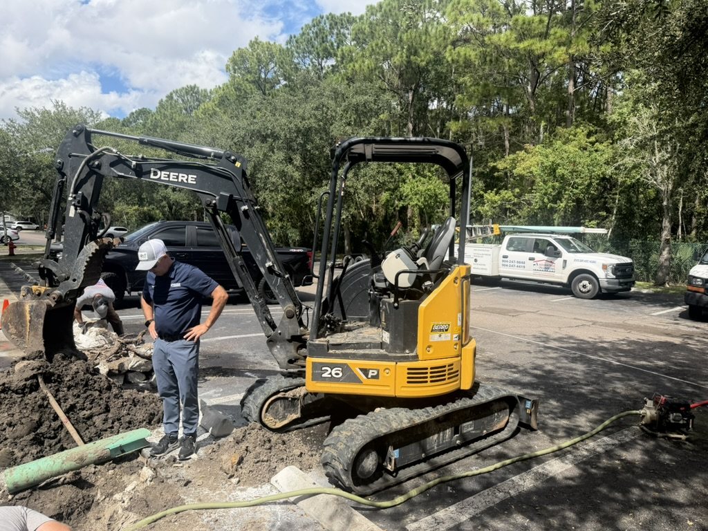 Advantage Plumbing team and excavator at an apartment community water-line repair