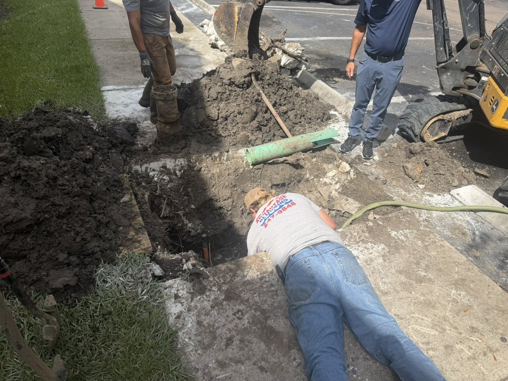 Advantage Plumbing technician working at the excavated apartment-community water line