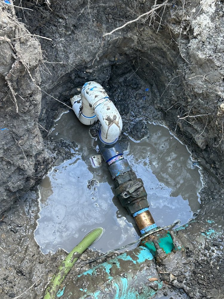 Repaired pipe connections visible in the apartment-community excavation