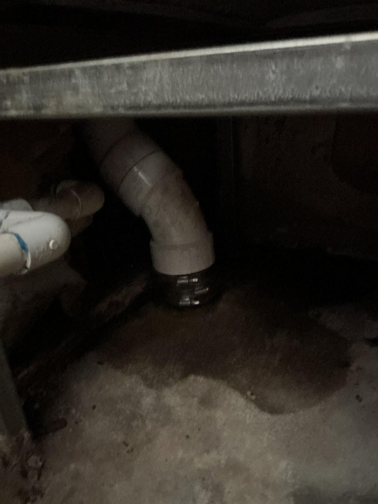 Replacement PVC drain fitting and connection installed in the tight wall space after the cast-iron repair