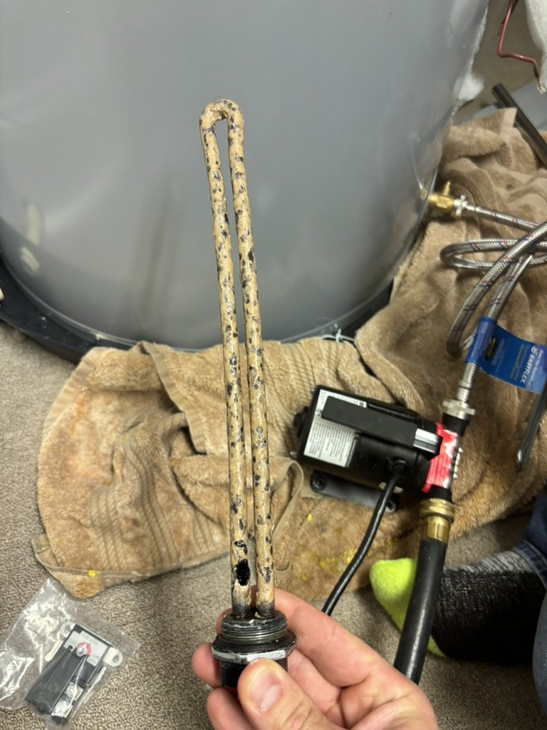 Removed water-heater heating element held beside the tank during an Advantage Plumbing repair