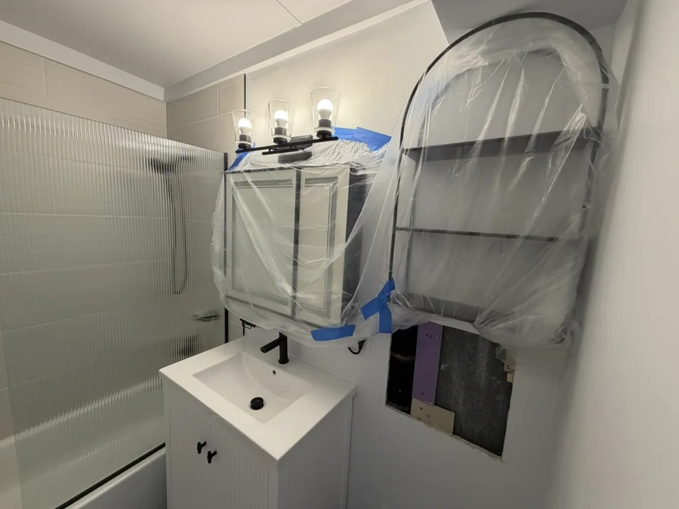 Bathroom mirrors and fixtures covered with protective plastic during a home repipe