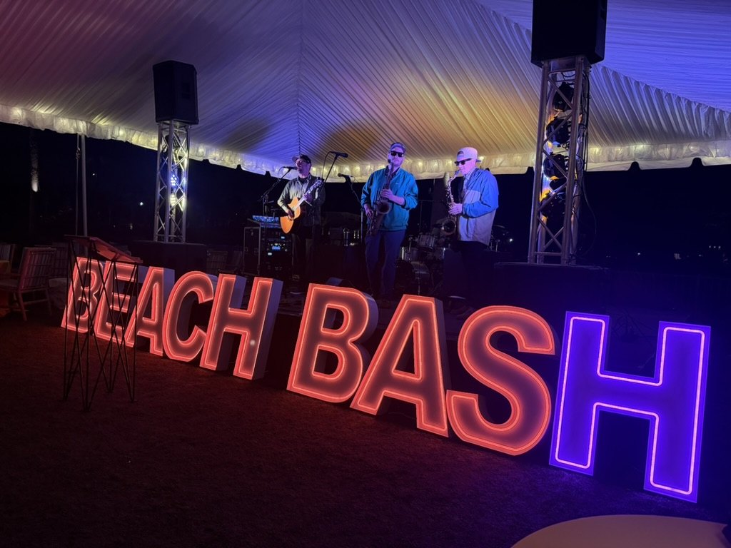 Musicians performing behind illuminated Beach Bash letters at the 2026 event
