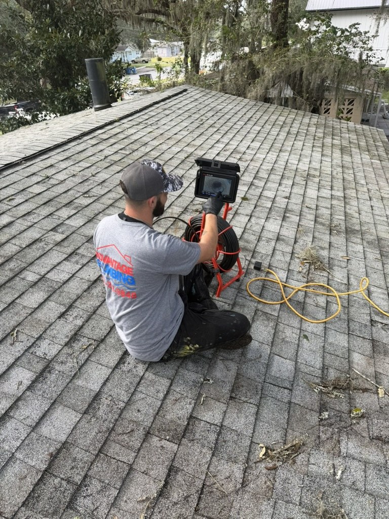 Advantage Plumbing technician reviewing a drain inspection camera monitor on the roof beside a plumbing vent