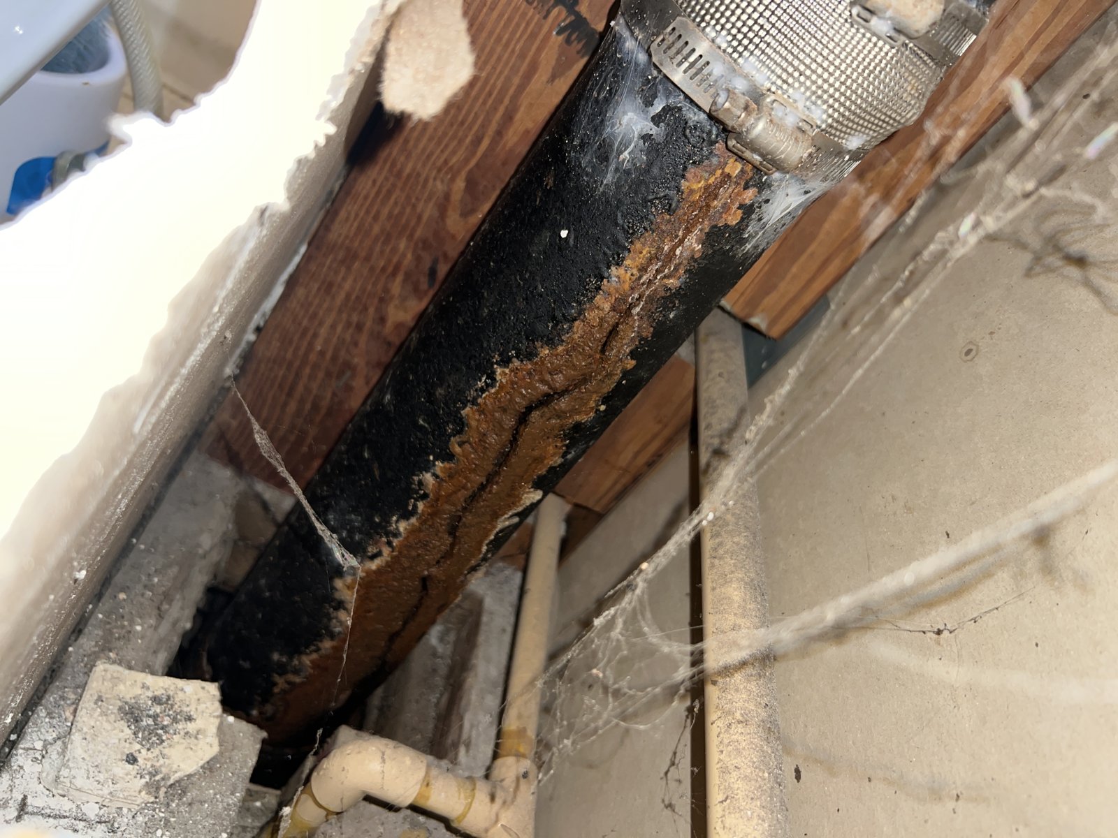 Cracked and corroded cast-iron stack exposed inside a wall cavity