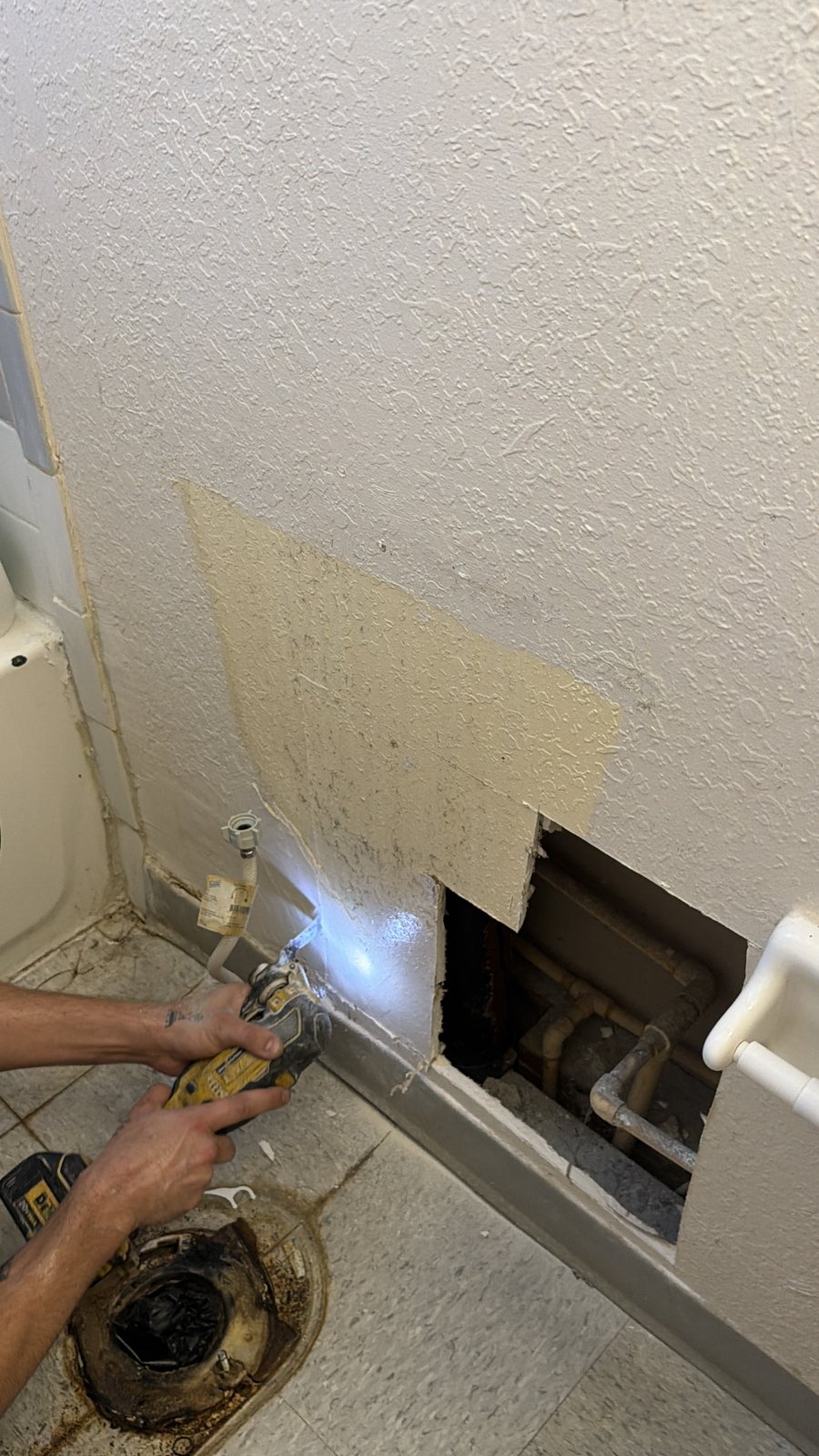Plumber enlarging the bathroom wall opening with the toilet removed