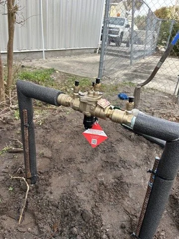 Installed backflow preventer connected to insulated outdoor water piping