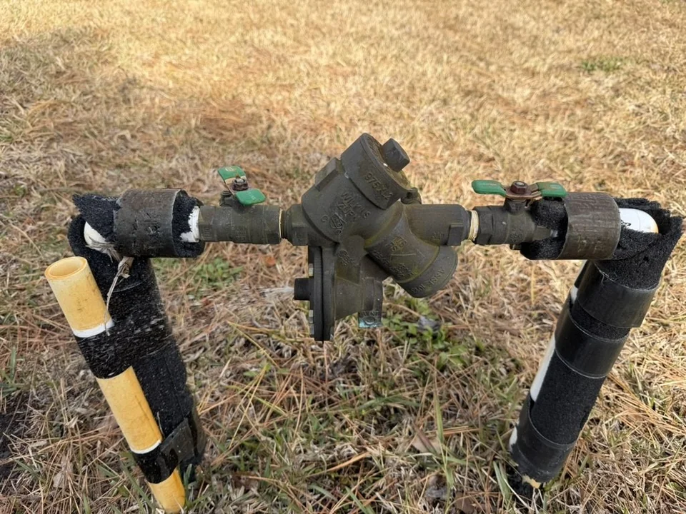 Broken backflow preventer before replacement, connected to outdoor piping
