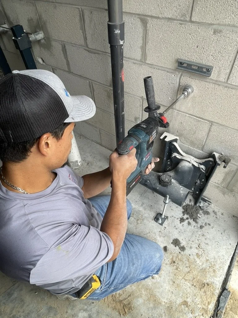 Advantage Plumbing technician drilling mounting points beside a commercial toilet carrier