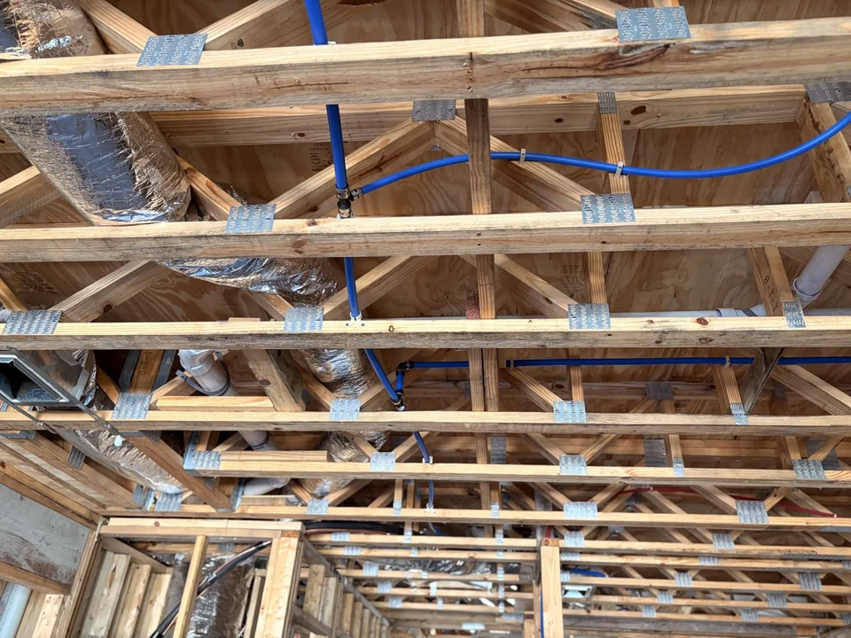 Water supply lines routed through overhead framing during construction