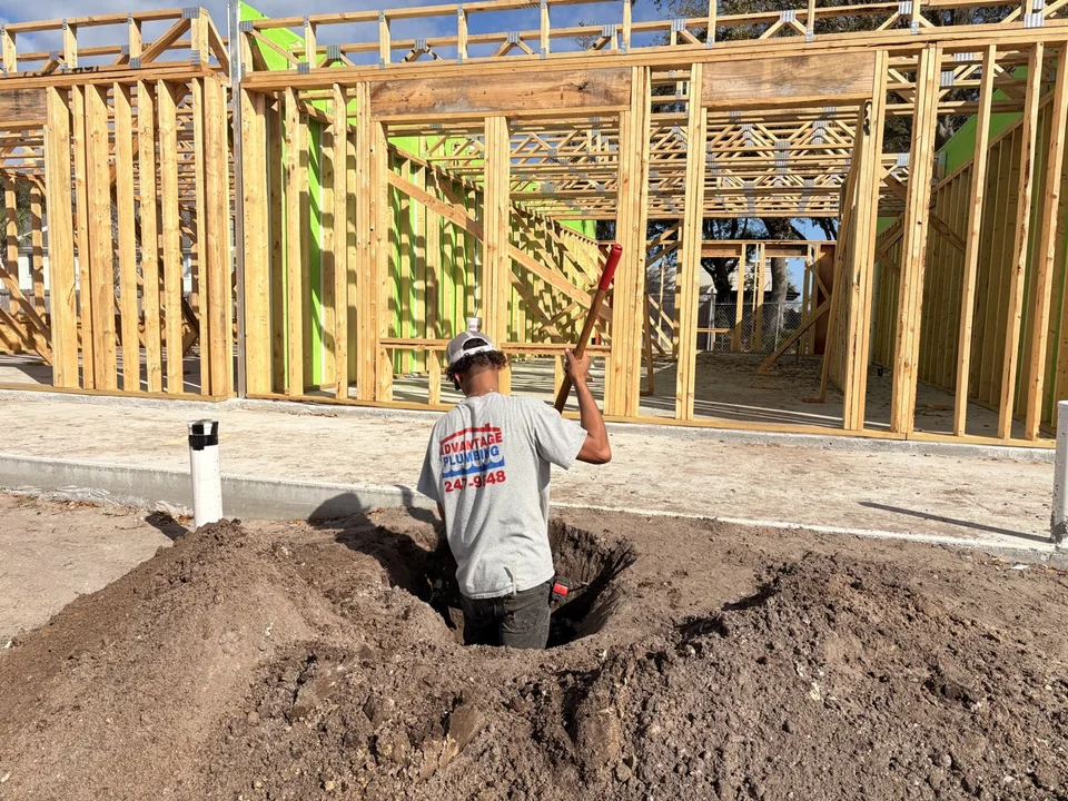 Advantage Plumbing technician working in a plumbing trench inside a framed building