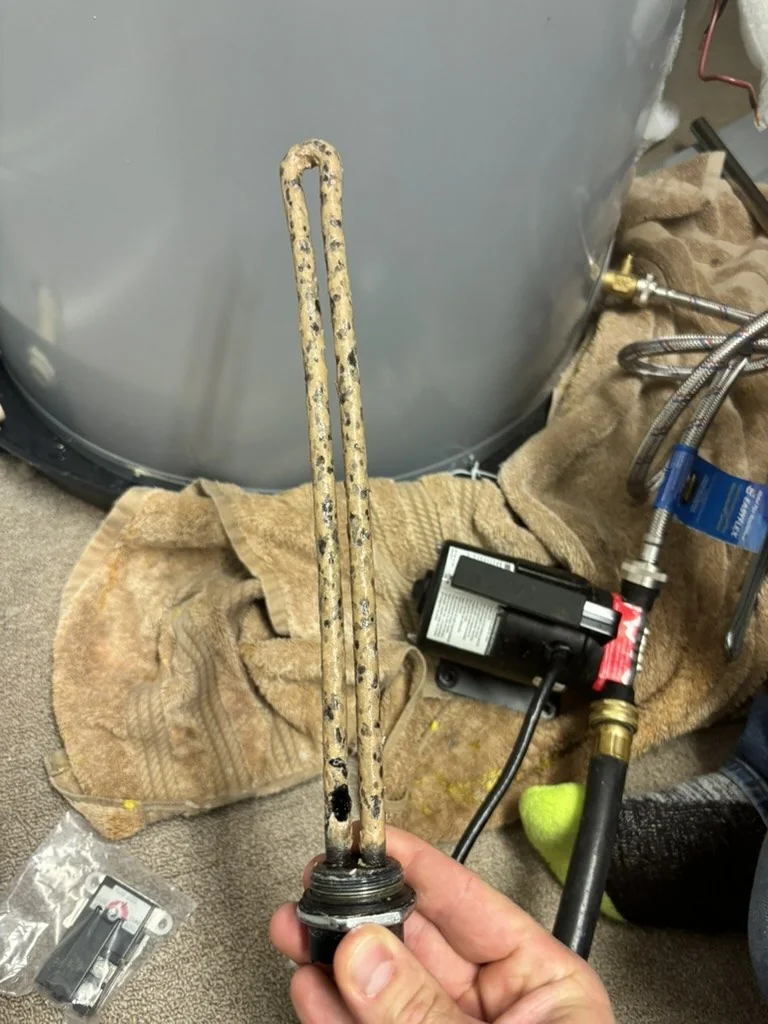 Cracked and corroded electric water heater element removed during a repair