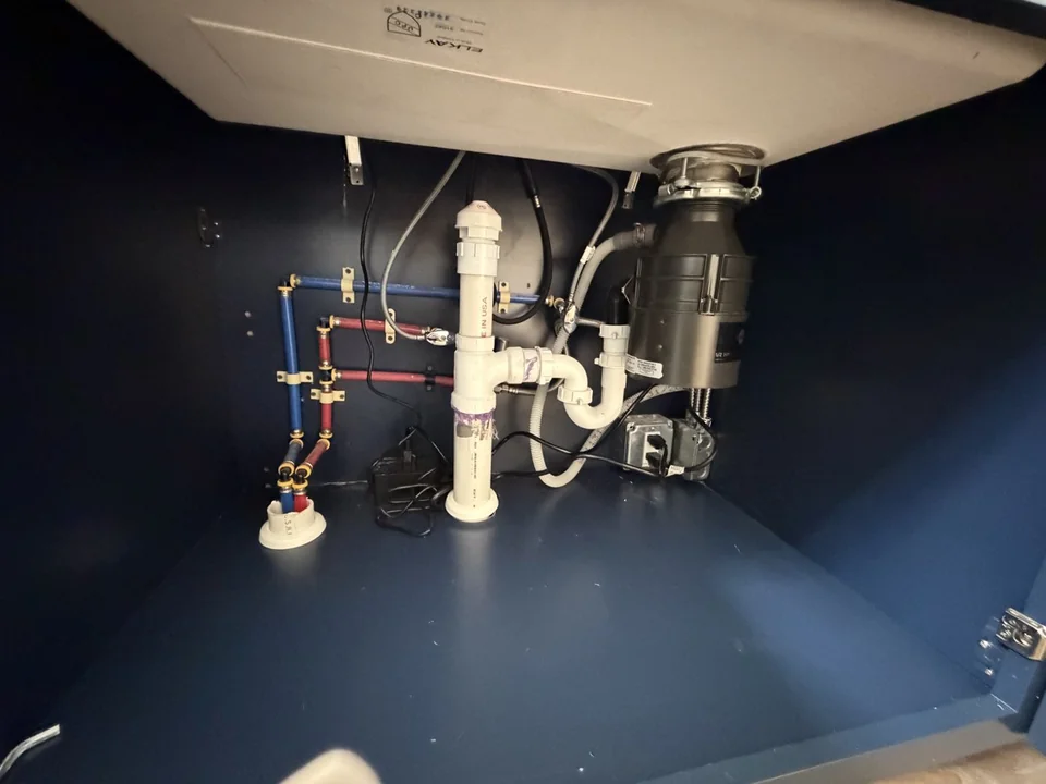 Garbage disposal and drain connections installed beneath a kitchen sink by Advantage Plumbing